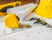 15-construction-plans-with-yellow-helmet-and-drawing-tools-on-bluep.jpg