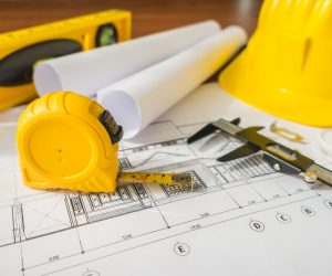 15-construction-plans-with-yellow-helmet-and-drawing-tools-on-bluep.jpg